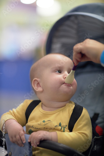 a one-year-old child, a boy, eats on the road, has a snack on the way in a stroller