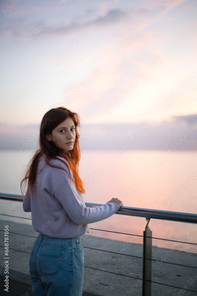 Young woman looking at camera in front of the sea at sunrise.