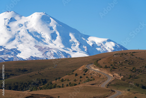 A winding road in the mountains-way to a snow-covered volcano. Copy space.
