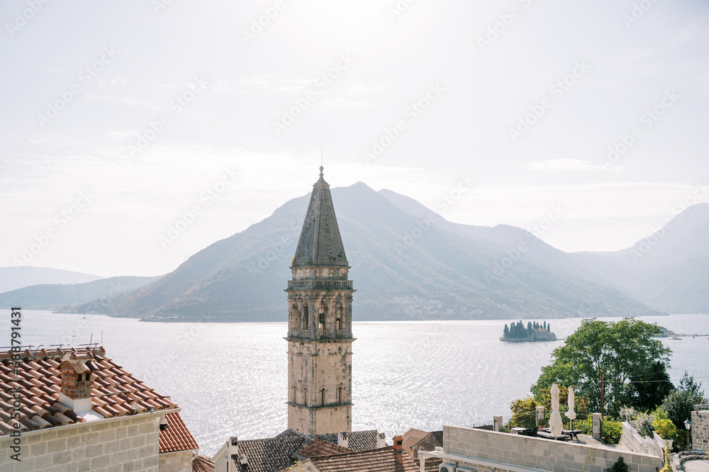 High bell tower of the Church of St. Nicholas against the backdrop of mountains and the sea. Perast, Montenegro