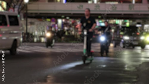 TOKYO, JAPAN - NOV 2023 : View of people riding on rental electric scooter (electric kickboard) at the street. Blurred shot. photo