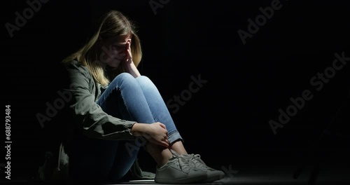 Fear, stress or anxiety with a girl in the dark as a kidnap victim for the crime human trafficking. Sad, scared or crying and an abused youth on a black background with mockup space at night photo