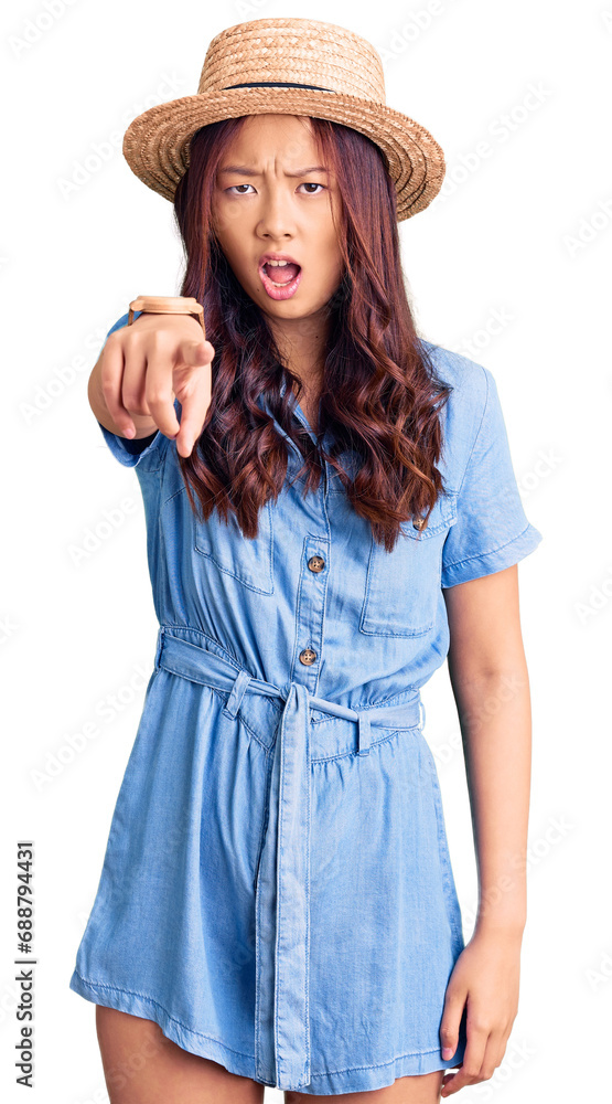 Young beautiful chinese girl wearing summer hat pointing displeased and frustrated to the camera, angry and furious with you Young beautiful chinese girl wearing summer hat pointing displeased and frustrated to the camera, angry and furious with you