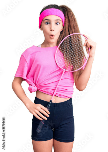Cute hispanic child girl holding badminton racket scared and amazed with open mouth for surprise, disbelief face © Krakenimages.com