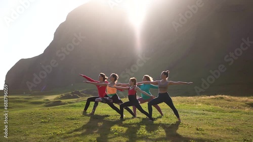 A group of girls doing yoga at sunset in the mountains
