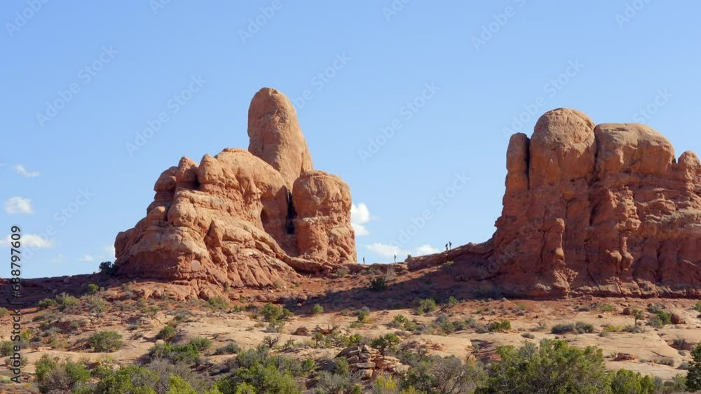 Establishing shot of mountain trail with red rocks background in Double Arch, Arches National Park, Utah, North America. Day time on October 2023. Still camera view. ProRes 422 HQ. Establishing shot of mountain trail with red rocks background in Double Arch, Arches National Park, Utah, North America. Day time on October 2023. Still camera view. ProRes 422 HQ.