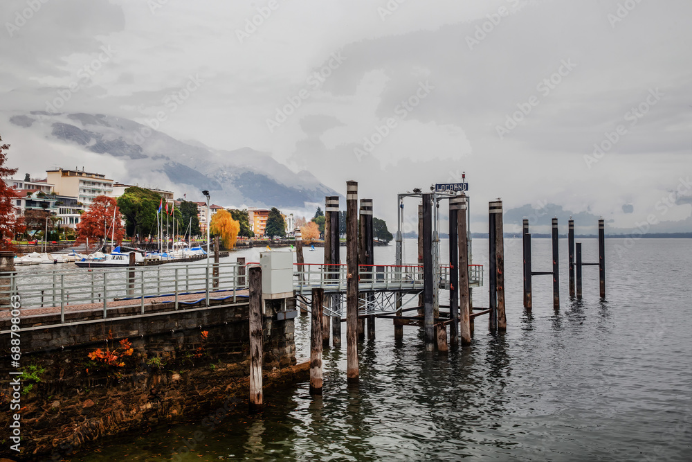 Pier and coastline on lake Maggiore and park there and buildings of Locarno