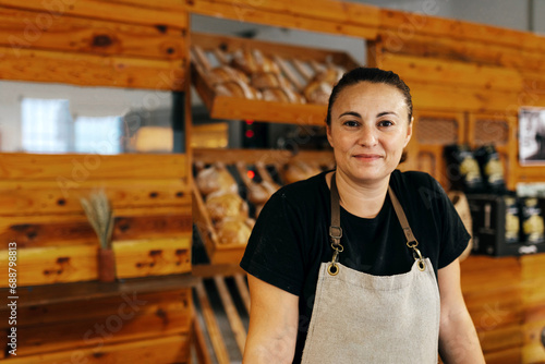 Happy saleswoman standing by bread in bakery shop photo