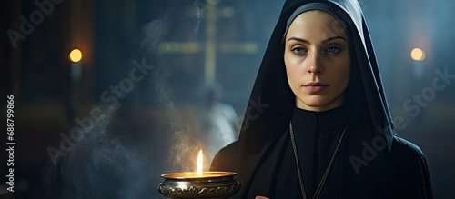 Orthodox Christian nun holding a smoking censer with shallow depth. photo