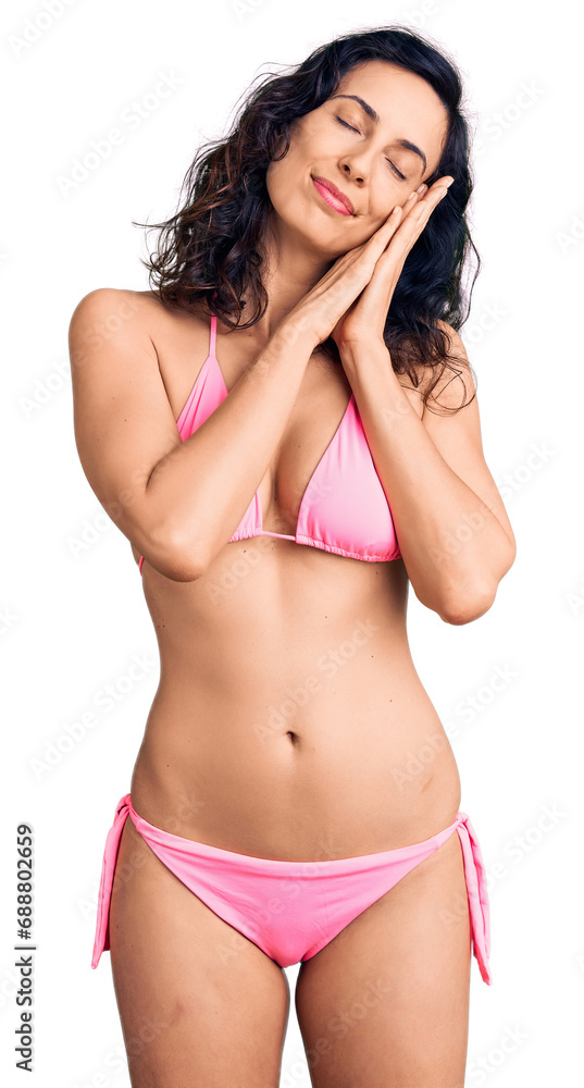 Fototapeta premium Young beautiful hispanic woman wearing bikini sleeping tired dreaming and posing with hands together while smiling with closed eyes.