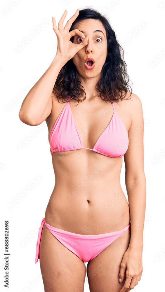 Young beautiful hispanic woman wearing bikini doing ok gesture shocked with surprised face, eye looking through fingers. unbelieving expression. Young beautiful hispanic woman wearing bikini doing ok gesture shocked with surprised face, eye looking through fingers. unbelieving expression.