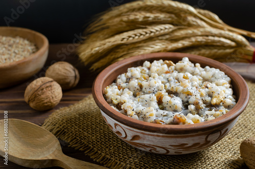 Kutya, a traditional Christmas Ukrainian dish of wheat groats on the table for Christmas or the old new year. Boiled porridge with walnuts, raisins, poppy seeds and honey. Rustic style. photo