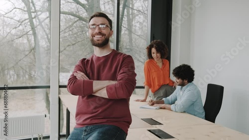 Confident portrait of Caucasian handsome stylish man in casual wear, wearing trendy glasses, smiling looking confidently at camera standing in corporate office. People. Corporate business. Profession