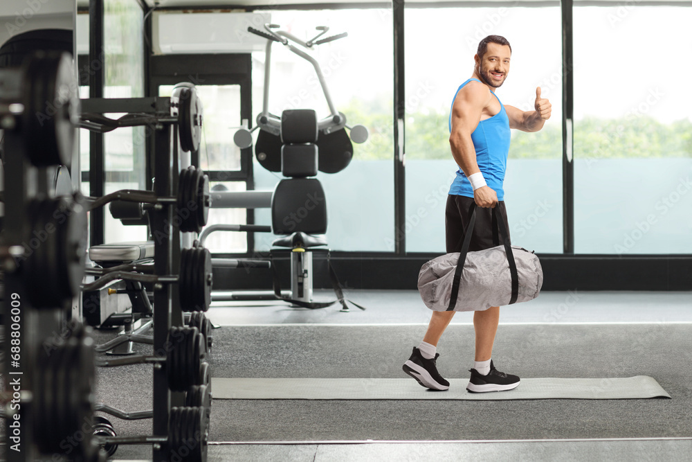 Man with a sports bag gesturing thumbs up and smiling Man with a sports bag gesturing thumbs up and smiling
