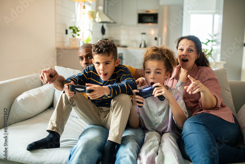 Children playing video games with parents watching at home photo