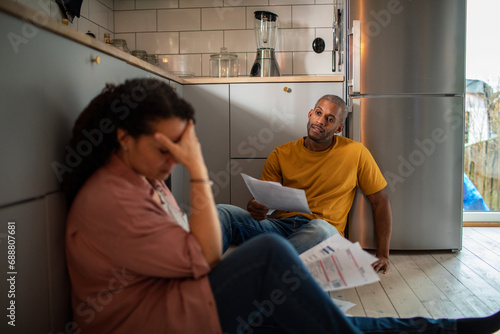 Stressed upset couple going over bills on kitchen floor photo