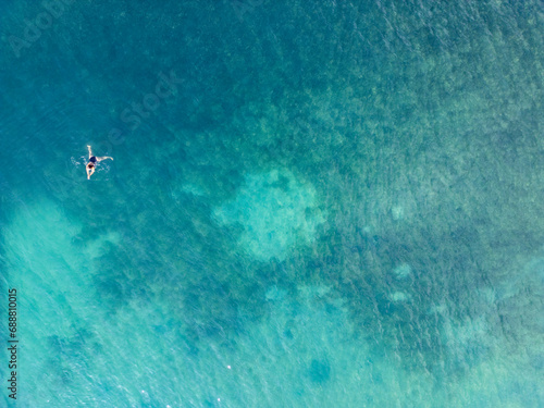 Aerial view of a person floating in clear azure waters photo
