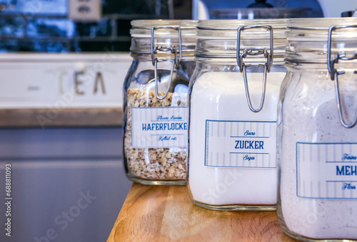 Kitchen jars with labeled pantry staples on a wooden shelf