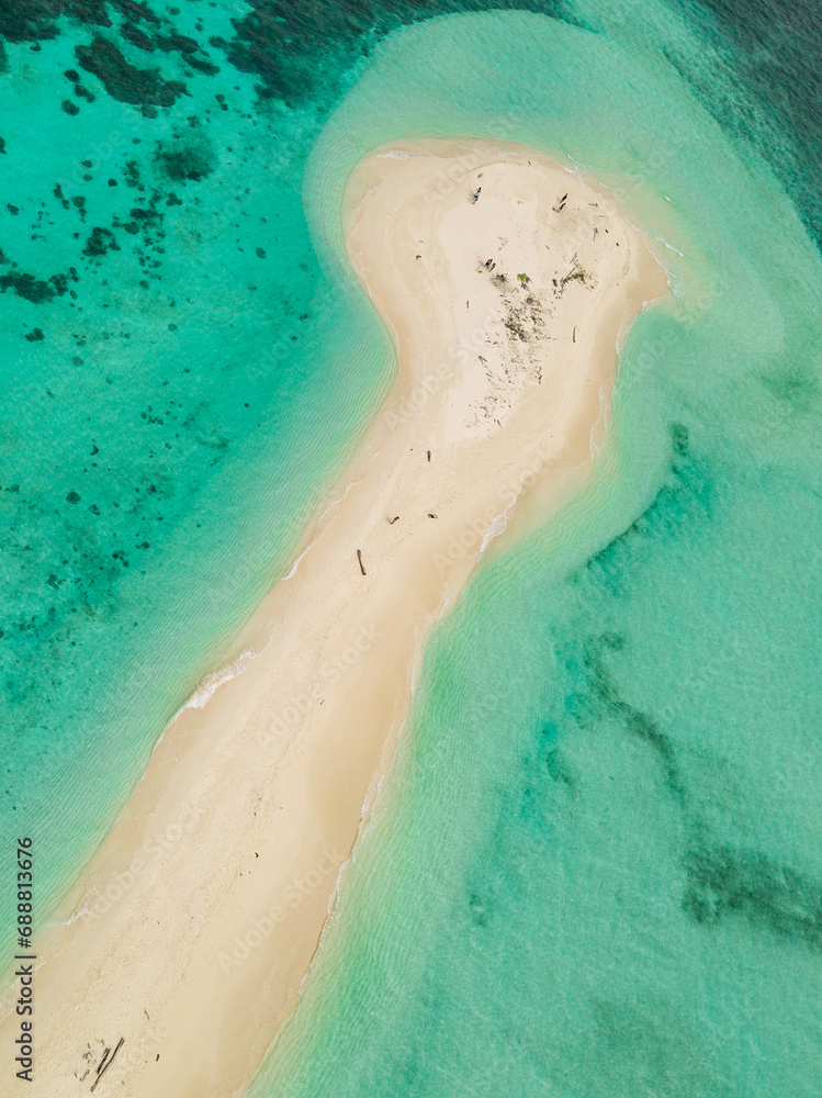 Drone shot over a tropical beach with blue water
