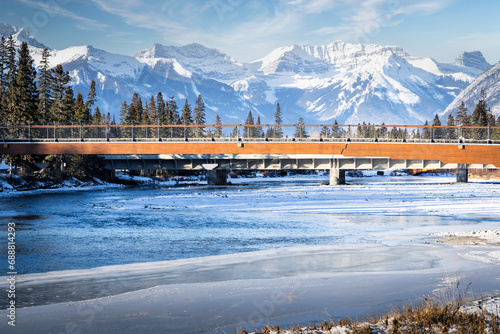 Pedestrian bridge crosses the Bow River overlooking the Canadian Rocky Mountains in Banff Alberta Canada.