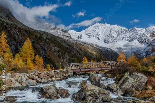 The alpine creek flow in front of the highness of the snow capped Alps.