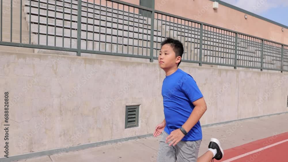 12 year old boy runs on his school's track. 12 year old boy runs on his school's track.