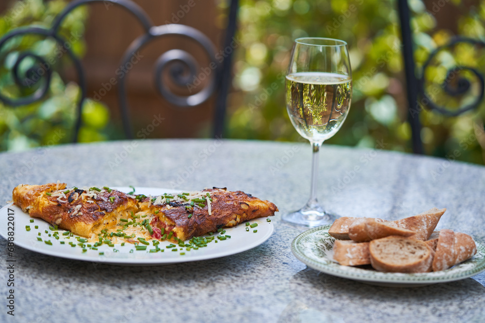 French style omelette with cheese and choped chives served as a light and quick lunch outside in the garden restaurant or french bistro with slices of whole grain baguette and glass of white wine. French style omelette with cheese and choped chives served as a light and quick lunch outside in the garden restaurant or french bistro with slices of whole grain baguette and glass of white wine.