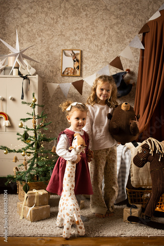 sisters playing with toy animals at children's room on Christmas decorated home