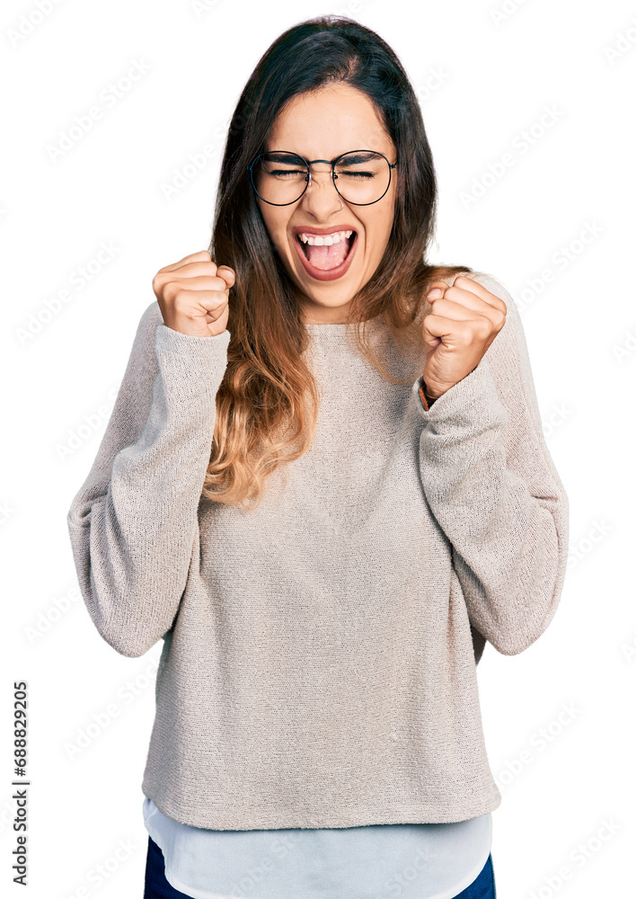 Beautiful hispanic woman wearing casual sweater and glasses excited for success with arms raised and eyes closed celebrating victory smiling. winner concept. Beautiful hispanic woman wearing casual sweater and glasses excited for success with arms raised and eyes closed celebrating victory smiling. winner concept.