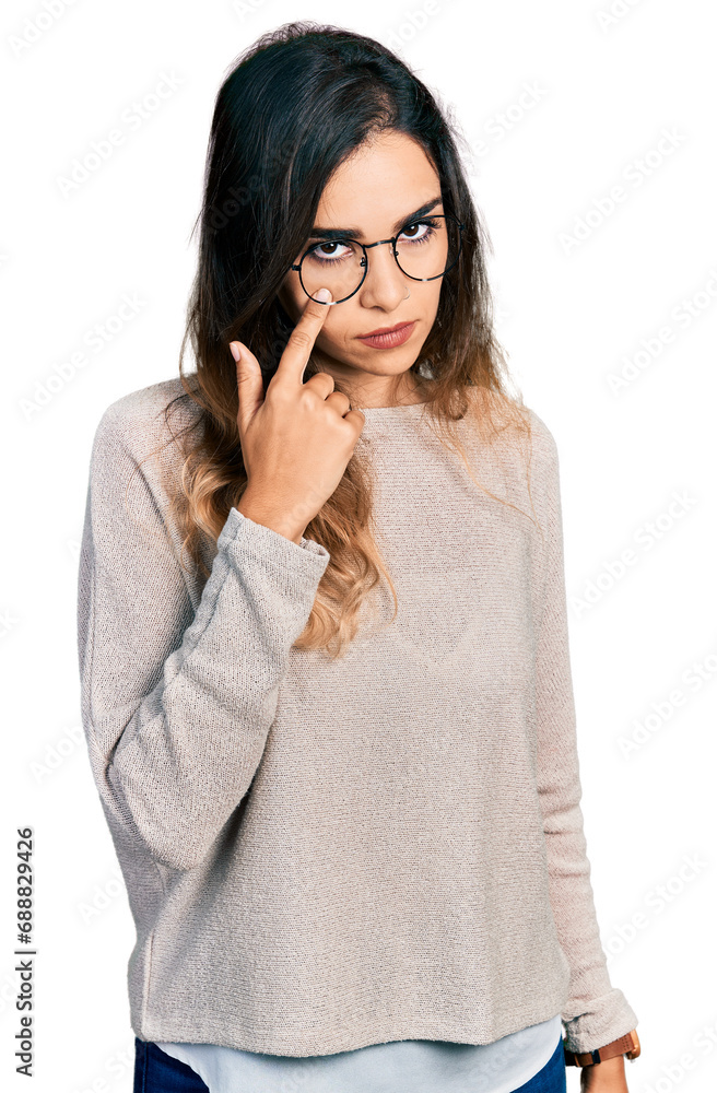 Beautiful hispanic woman wearing casual sweater and glasses pointing to the eye watching you gesture, suspicious expression Beautiful hispanic woman wearing casual sweater and glasses pointing to the eye watching you gesture, suspicious expression