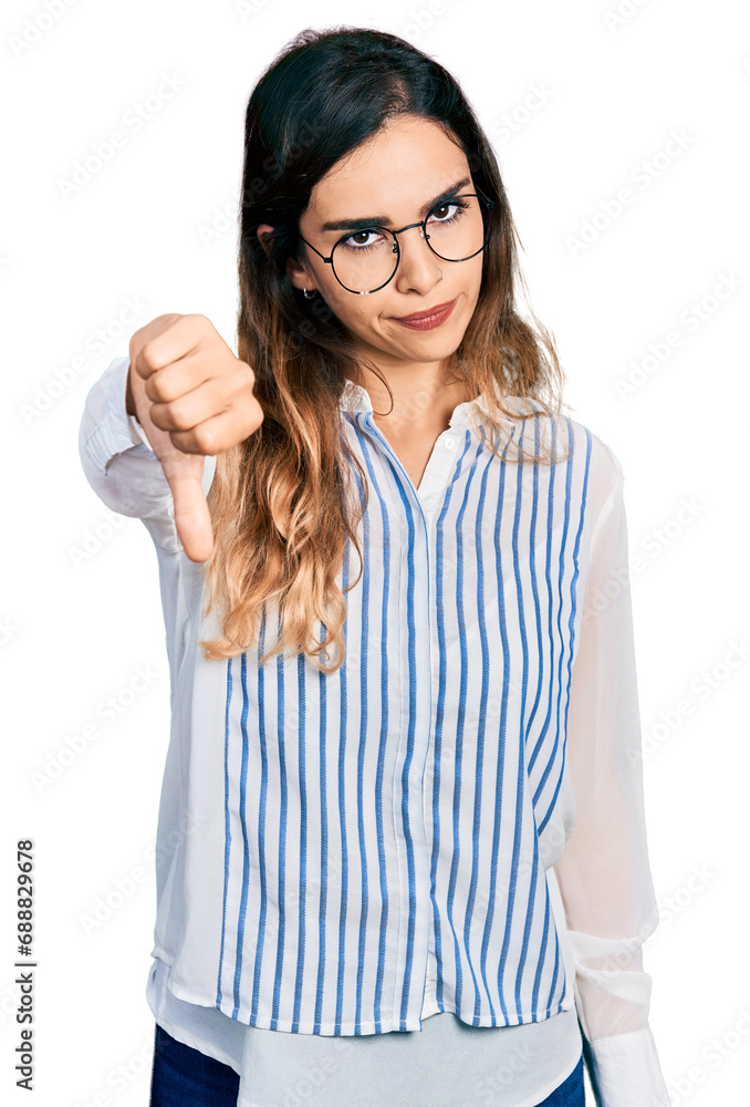 Beautiful hispanic woman wearing casual striped shirt looking unhappy and angry showing rejection and negative with thumbs down gesture. bad expression. Beautiful hispanic woman wearing casual striped shirt looking unhappy and angry showing rejection and negative with thumbs down gesture. bad expression.