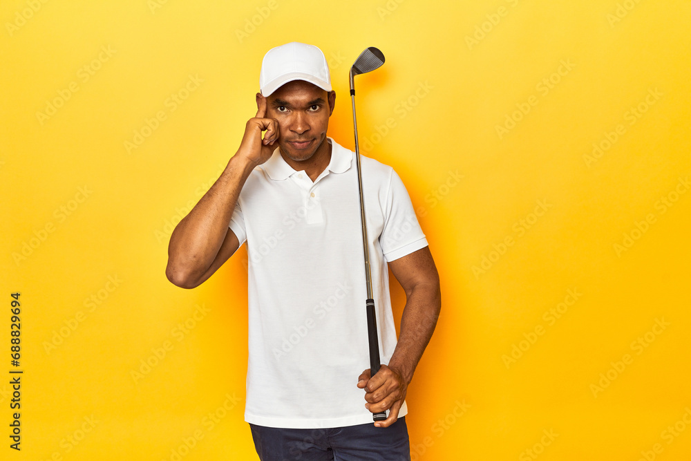 African American man golfer, yellow studio backdrop, pointing temple with finger, thinking, focused on a task.