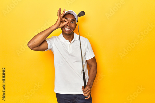 African American man golfer, yellow studio backdrop, excited keeping ok gesture on eye.