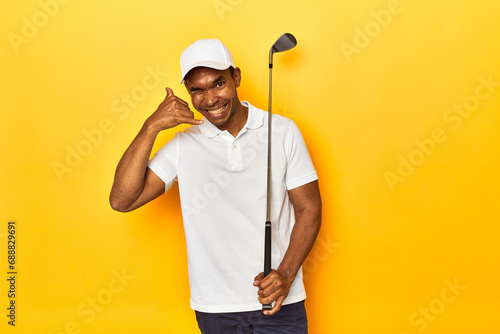 African American man golfer  yellow studio backdrop  showing a mobile phone call gesture with fingers.