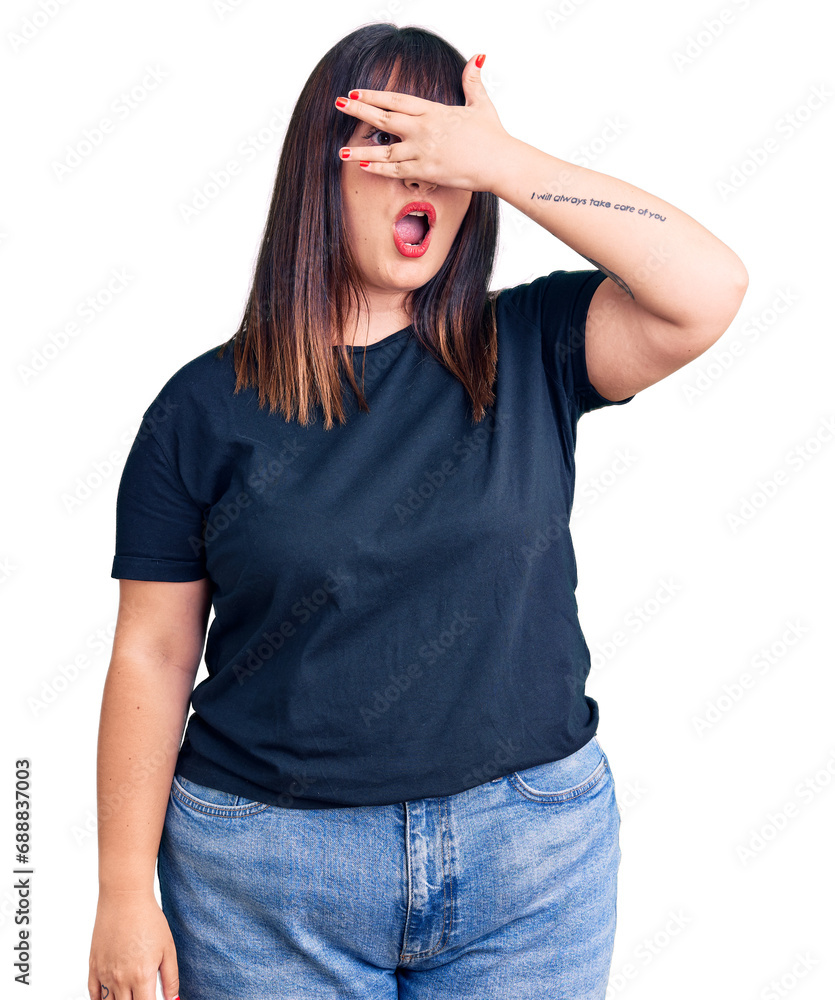 Young plus size woman wearing casual clothes peeking in shock covering face and eyes with hand, looking through fingers with embarrassed expression. Young plus size woman wearing casual clothes peeking in shock covering face and eyes with hand, looking through fingers with embarrassed expression.