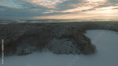 Aerial drone flight over snow covered forest in winter, cold weather, peaceful relaxing view during sunset or sunrise