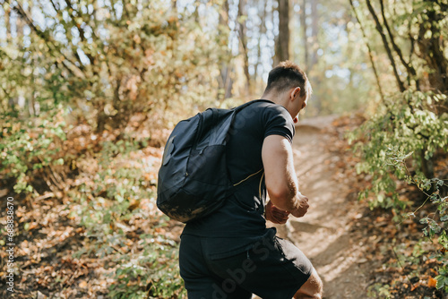 A male hiker enjoys an active day off in nature, exploring the wilderness. He exercises outdoors, embracing the fresh air and green environment.