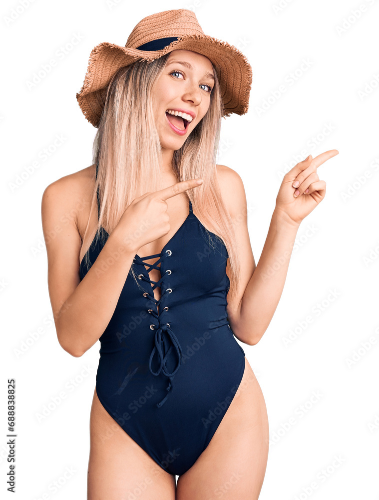 Φωτογραφία Young beautiful blonde woman wearing swimwear and summer hat smiling and looking at the camera pointing with two hands and fingers to the side