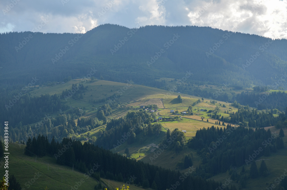 Sunlight and clouds over the summer mountains covered green forest and grassy slopes of mountain range. Carpathian Mountains, popular travel destination of Ukraine