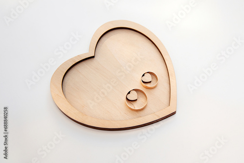 Rings arranged on a wooden heart-shaped stand against a white background.