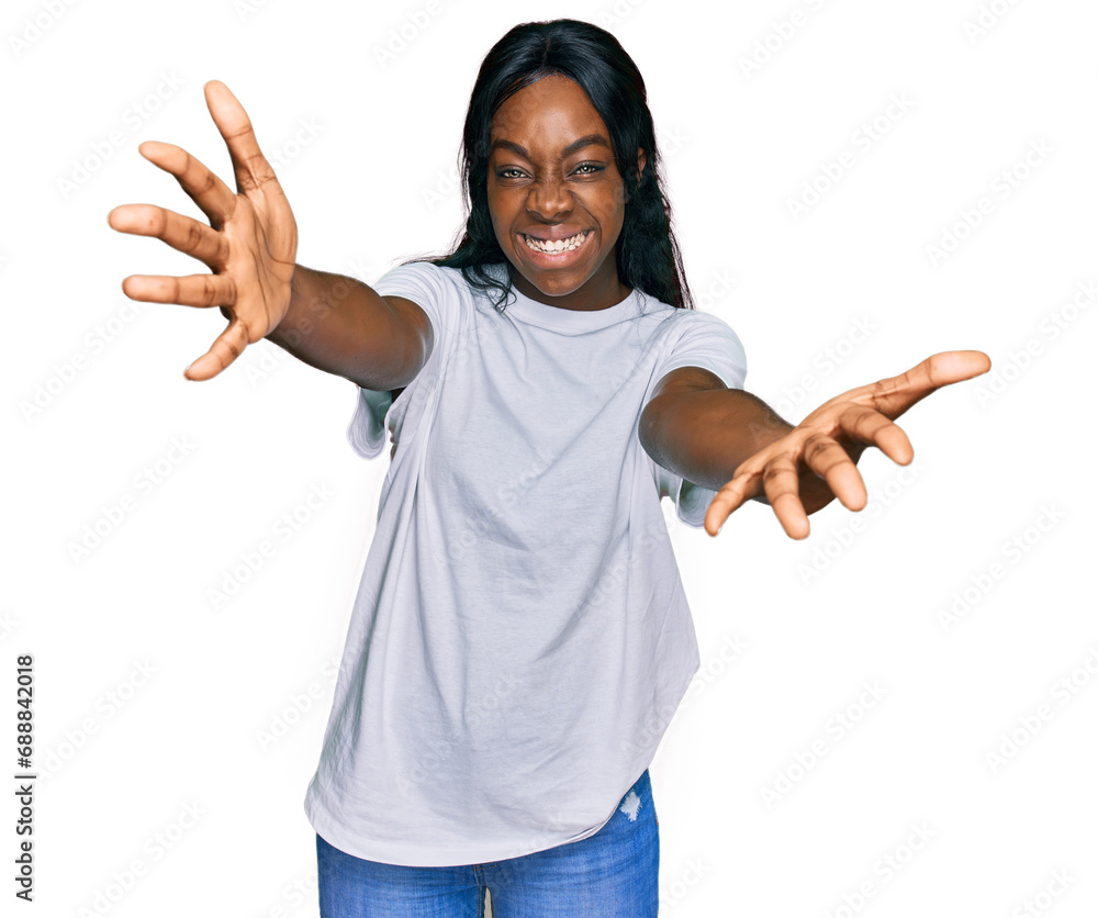 Young african american woman wearing casual white t shirt looking at the camera smiling with open arms for hug. cheerful expression embracing happiness. Young african american woman wearing casual white t shirt looking at the camera smiling with open arms for hug. cheerful expression embracing happiness.