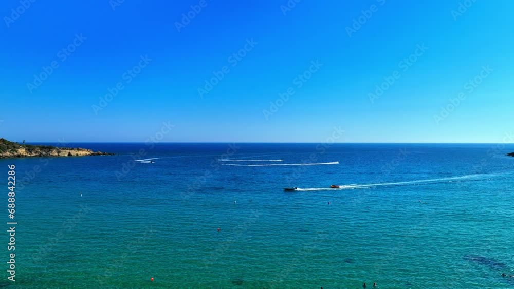 Aerial Shot Of Tourists Enjoying In Sea At Beach Against Clear Sky, Drone Flying Forward During Sunny Day - Paphos, Cyprus Aerial Shot Of Tourists Enjoying In Sea At Beach Against Clear Sky, Drone Flying Forward During Sunny Day - Paphos, Cyprus