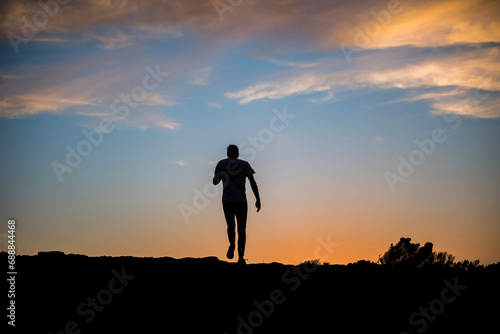 A silhouette as a man walks on a rock face at sunset