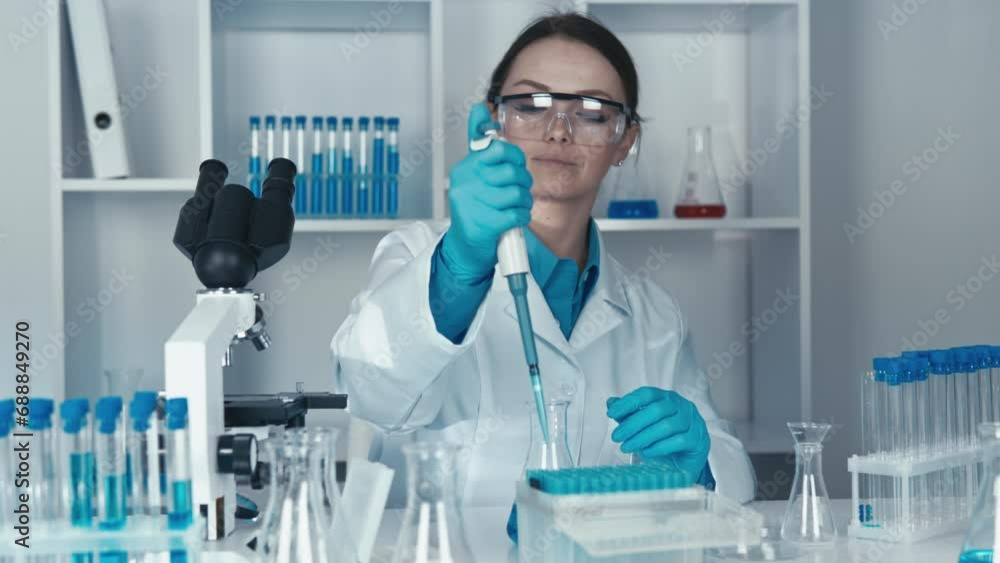 The researcher is working to develop a new treatment using cutting-edge technology and molecular biology. She picks up pipette with a dispenser from a flask in laboratory of chemistry and medicine. The researcher is working to develop a new treatment using cutting-edge technology and molecular biology. She picks up pipette with a dispenser from a flask in laboratory of chemistry and medicine.