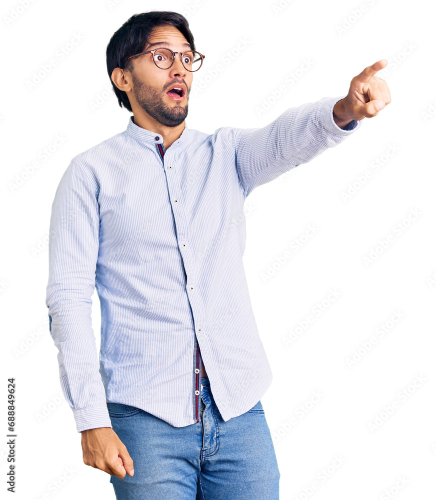 Handsome hispanic man wearing business shirt and glasses pointing with finger surprised ahead, open mouth amazed expression, something on the front Handsome hispanic man wearing business shirt and glasses pointing with finger surprised ahead, open mouth amazed expression, something on the front