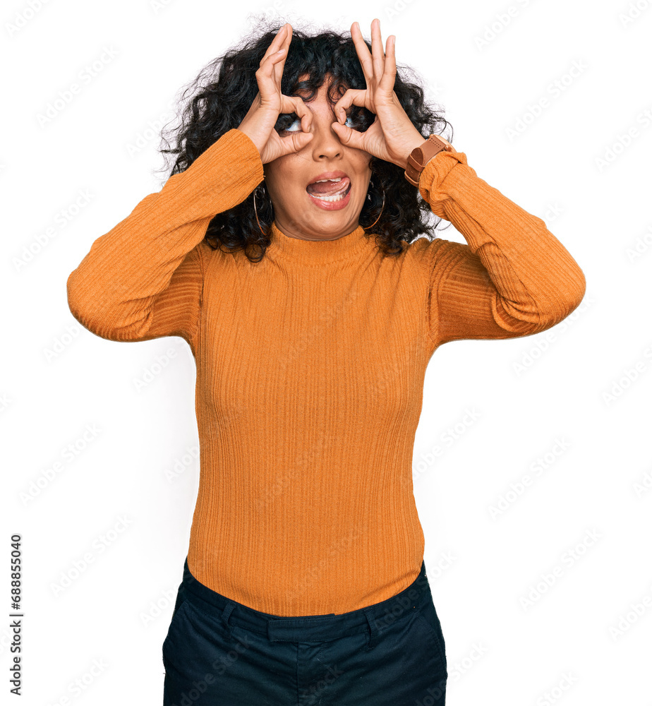 Young hispanic woman wearing casual clothes doing ok gesture like binoculars sticking tongue out, eyes looking through fingers. crazy expression. Young hispanic woman wearing casual clothes doing ok gesture like binoculars sticking tongue out, eyes looking through fingers. crazy expression.