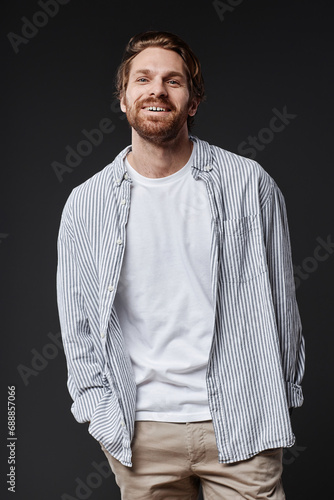 Vertical portrait of smiling bearded man looking at camera with carefree face expression in studio