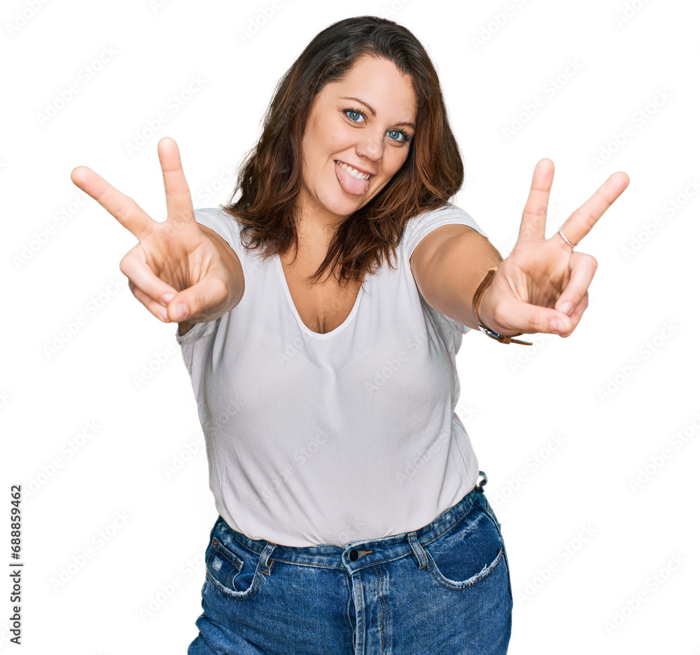 Young plus size woman wearing casual white t shirt smiling with tongue out showing fingers of both hands doing victory sign. number two. Young plus size woman wearing casual white t shirt smiling with tongue out showing fingers of both hands doing victory sign. number two.