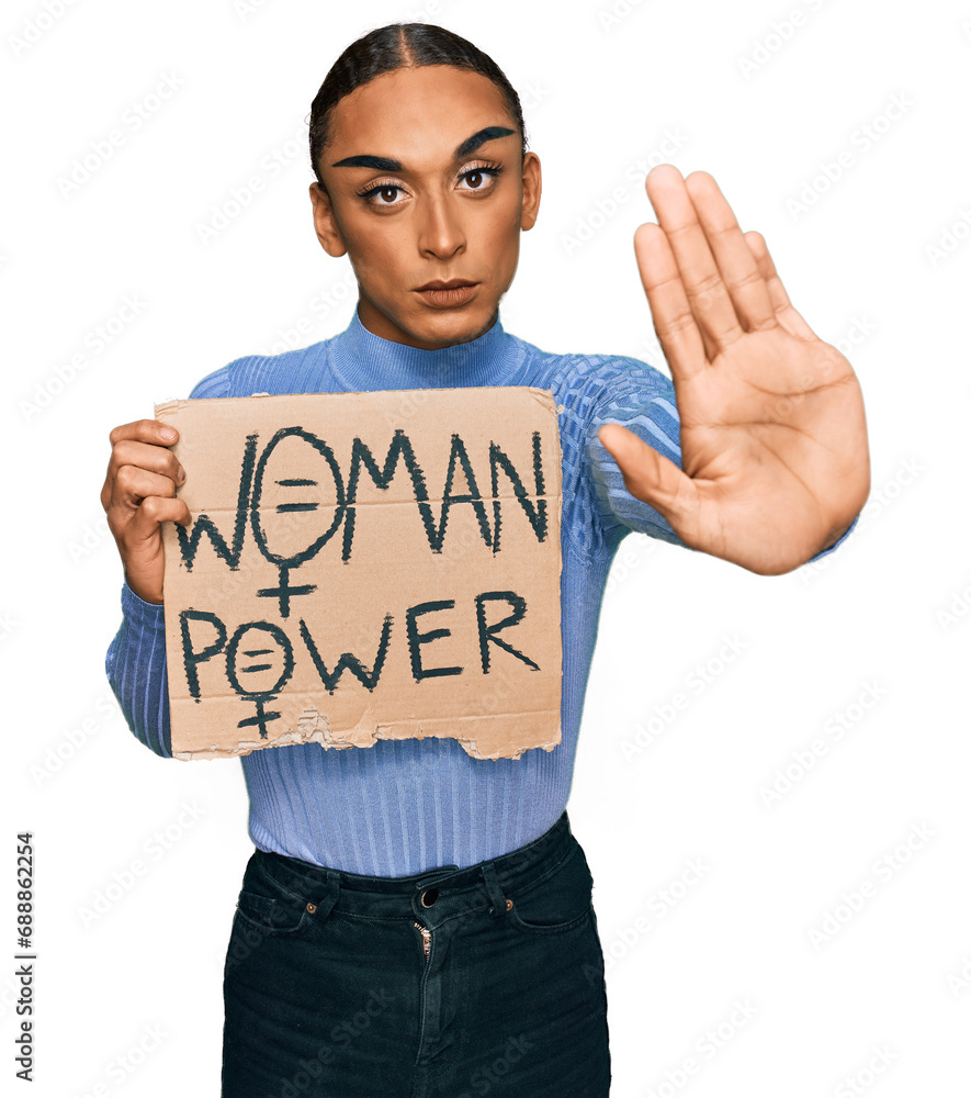 Hispanic transgender man wearing make up and long hair holding we need a change banner with open hand doing stop sign with serious and confident expression, defense gesture Hispanic transgender man wearing make up and long hair holding we need a change banner with open hand doing stop sign with serious and confident expression, defense gesture