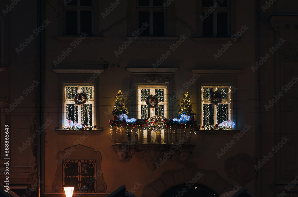 The night balcony with windows is decorated with garlands and fir branches on New Year's Eve and Christmas. Lviv, Ukraine.